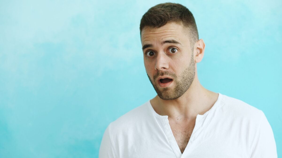 A surprised man in a white shirt with a blue background.