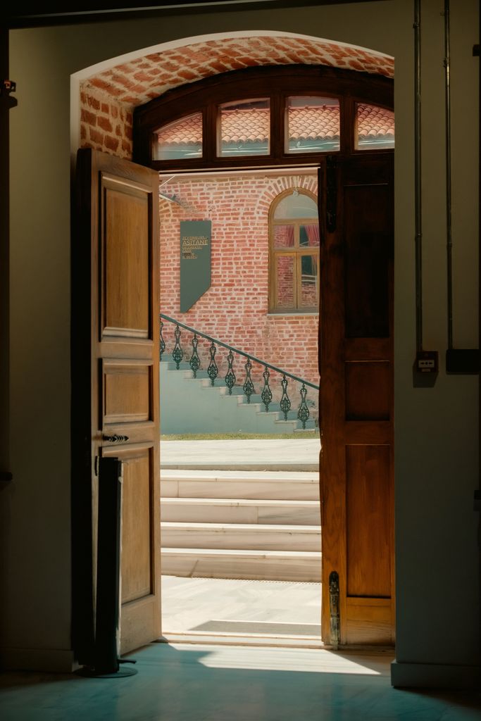 A wooden door opens to reveal a rustic brick building with steps. Warm and inviting.