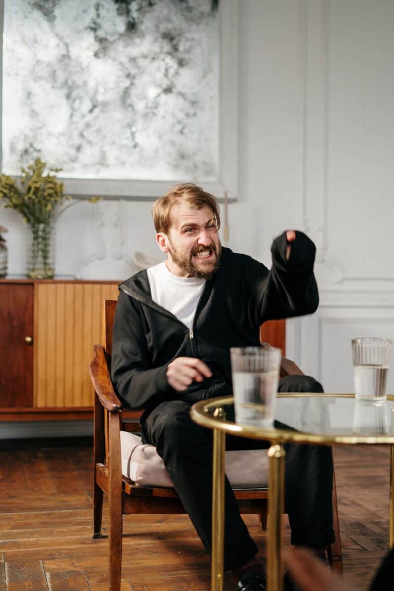 An angry man expressing emotion during a therapy session indoors.