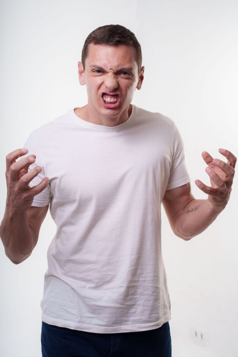 Angry young man clenching fists with a fierce expression. Studio portrait in Curitiba, Brazil.