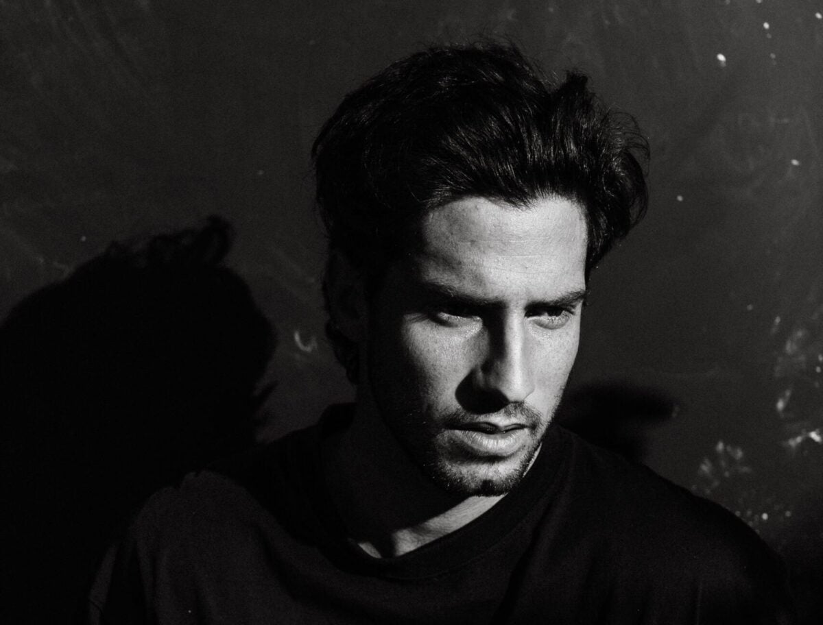 Black and white of unshaven adult male with thoughtful gaze in casual wear looking away