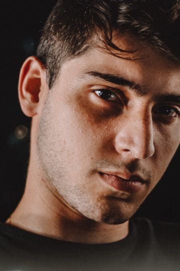 Close-up moody portrait of a young man with intense gaze captured at night.