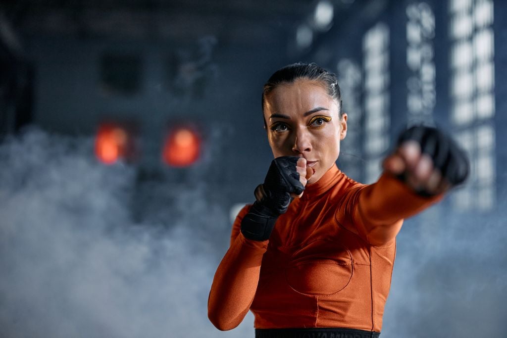 Focused woman in activewear practicing boxing in a smoky indoor setting.