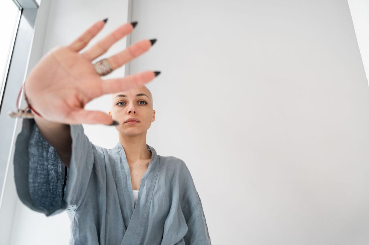 From below of young female in robe demonstrating control gesture while looking at camera in hospital on white background