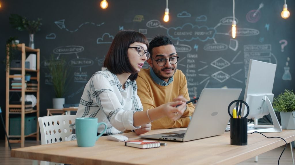 Two coworkers collaborating on a project in a trendy office.