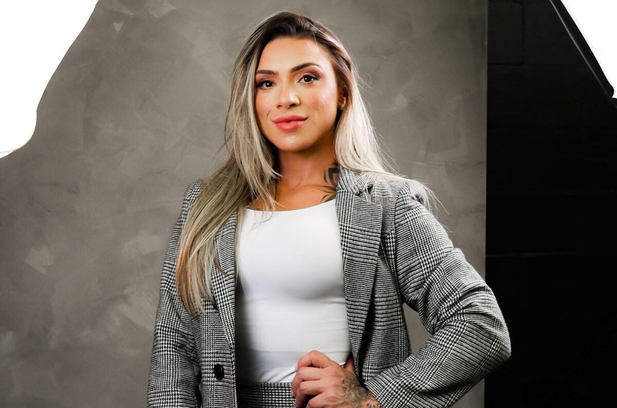 Woman posing confidently in a modern studio wearing elegant business attire, exuding professionalism.