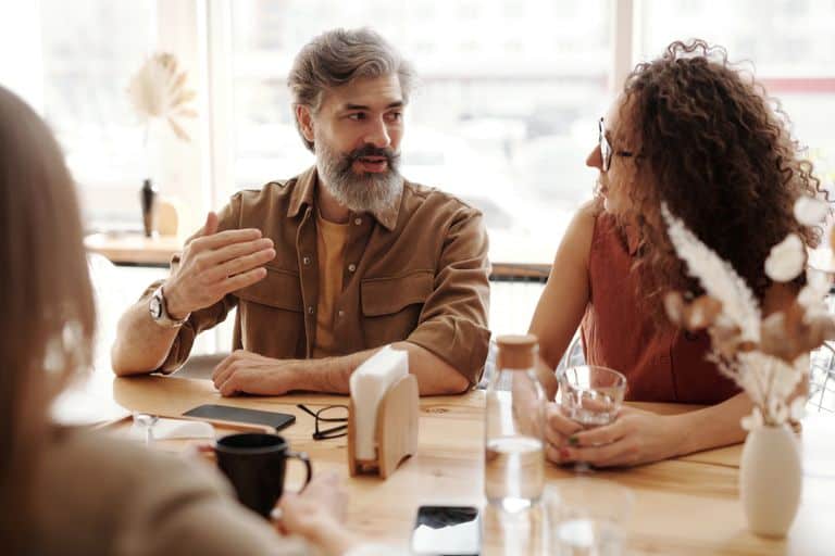 A friendly discussion among colleagues in a cozy cafe environment, fostering teamwork and collaboration.