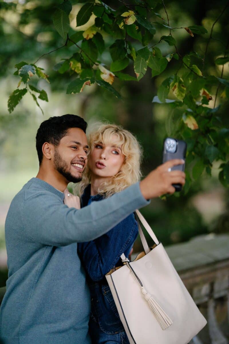 A happy couple taking a selfie together in a lush outdoor setting, showcasing joy and companionship.