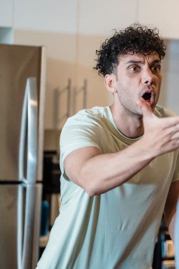 A stressed couple arguing in a modern kitchen, highlighting relationship issues.