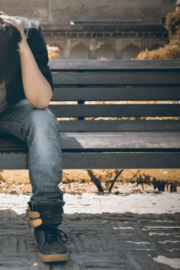 Man sitting alone on a bench in Agra, displaying signs of stress and loneliness.