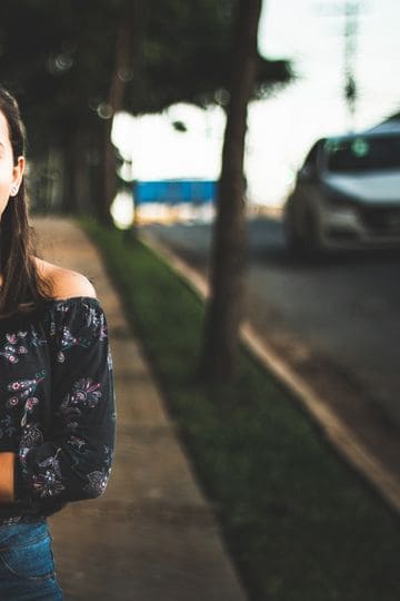 Smiling woman in casual wear posing confidently on a sunny city street.
